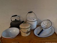 Photo of all six kitchenware items including kettle, two covered pots, colander, serving plate, and bowl.