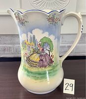 Front view of Falcon Ware pitcher showing the painted pastoral scene of a seated woman and floral decorations.