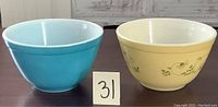 Side view of two Pyrex bowls, blue and yellow with pattern, labeled with number 31