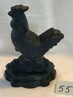 Front view of the cast iron chicken doorstop showing detailed feathers, comb, and scalloped base.
