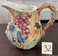 Front and side view of Fitz & Floyd ceramic pitcher with colorful raised grapevine design, showing grapes, leaf patterns, and twisted vine handle.