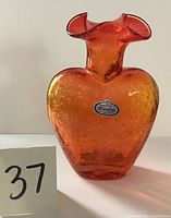 Front view showing the orange amberina crackle glass heart-shaped vase with original Rainbow Co. sticker