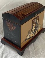 Side view of the wooden box showing the slatted hinged lid, dark stained frame, and painted side panel with text 'Happiness is a Warm Quilt'.
