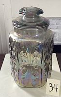 Front view of the carnival glass canister showing the iridescent surface and butterfly motif.