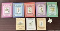 Photo showing 8 Beatrix Potter books arranged in two rows with titles clearly visible.