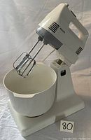 Philips stand mixer attached to the stand with beaters inserted, large white plastic mixing bowl on base.