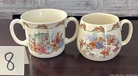 Front view showing the two Bunnykins cups with bunny illustrations and handles.