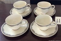 Set of four Royal Doulton Albany pattern teacups and matching saucers arranged on table, showing the full set.