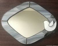 Front of the stained glass mirror showing diamond-shaped design with white dove and leaf accents on frame.