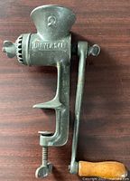 Side view of vintage Universal No. 2 grinder with clamp and wooden crank handle, showing branding and number