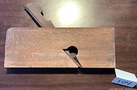 Front-facing view of the wooden moulding plane showing the blade and maker's marks on the end.