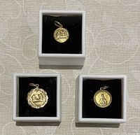 Photo of three gold pendants displayed in small white boxes with black velvet lining; shows overall lot contents and condition.