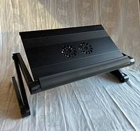 Front and top view of black adjustable laptop stand showing dual fans and front laptop stop lip.