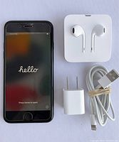 Front view of phone powered on to setup screen alongside charger, cable, sealed EarPods