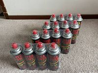 Sixteen red-capped Mega Power butane canisters arranged on carpet, showing overall look and quantity