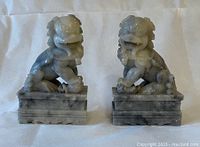 Front view of the pair of grayish stone Foo Dogs facing forward on bases.