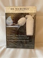 Front of the new unopened Dr. Mercola Pure & Clear Shower Filter showing product branding and claims.