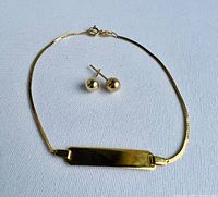 Overview of the ID bracelet laid flat next to two ball stud earrings