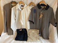 Full lot display of men's clothing including blazer, shirts, jeans and khakis all hung or folded on white background.