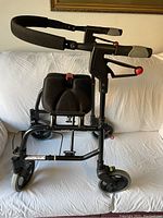 Side view of black Nexus rollator walker showing padded seat, adjustable handles with brakes, and front swivel wheel.