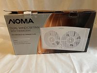 Box of NOMA Dual Window Fan with Thermostat showing product image and features.