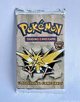 Front view of sealed booster pack showing Pokémon logo, Fossil set logo, Zapdos art and '11 additional game cards' text