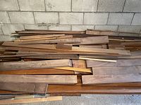 Pile of mixed-length wood boards leaning against cinderblock wall