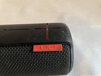 Close-up of black fabric mesh and red UE branded tag on the speaker.