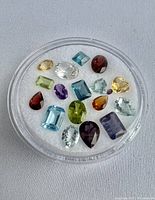 Overview of 15 faceted gemstones in round display case