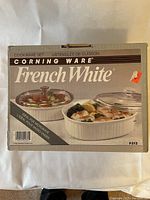Front of original box showing Corning Ware French White casserole set with 2 dishes and lids pictured.