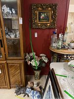 Full view of figurines including large ceramic cat, metal rabbit, small ceramic bunnies, ceramic dog, plaster pig, vase with faux flowers, and framed art on wall