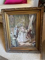 Frontal image of the framed cross stitch artwork showing detailed vintage style figures and ornate gold-tone frame.