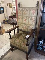 Full view of the antique throne chair, showing wooden frame and angel themed fabric upholstery.