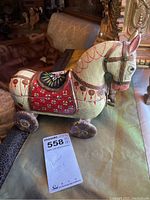 Right side view of the wooden horse toy showing red and cream hand-painted details and wheel decoration.