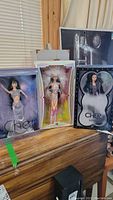 Three boxed Cher dolls displayed side by side on wooden surface