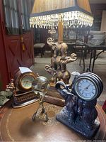 Photo showing tall elephant lamp with crystal-dangling square shade, two elephant quartz clocks and glass orb on brass tripod stand