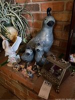 Three ceramic quail figurines displayed on brick hearth next to porcelain bird and decorative trinket boxes