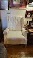 Front view of the white recliner showing the button tufted back and overall condition.