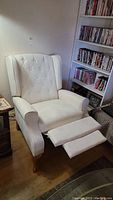 Full view of white reclining chair showing button tufted backrest, rolled arms, and extended footrest.