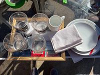 Top-down view of glasses, napkins, plates, and framed items on glass table