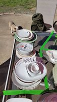 Stack of assorted vintage airline collector plates and cups on outdoor table.