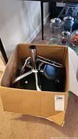 Disassembled chrome metal rolling chair base with wheels inside a cardboard box
