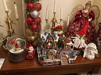 Photo showing the full set of Christmas decorations including the Santa village, snow globe, angel figurine, candelabra, and ornaments in vase.