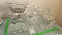 Four pinwheel crystal dishes and assorted glass serving dishes grouped together on a surface under neutral light showing clear detail of starburst and geometric cut patterns.