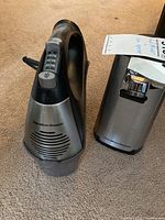 Photo showing the two kitchen appliances side by side on a carpeted floor: the electric hand mixer and electric can opener, both Hamilton Beach brand.