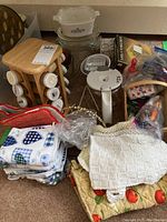 Overview of kitchen items including glass and CorningWare bowls, coffee pot, spice rack with jars, and folded kitchen linens.