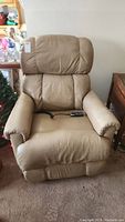 Front view of beige leather Lazyboy recliner chair showing overall condition and wear on leather.