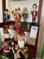 Overall view of seven assorted nutcracker figurines on two shelves, showing variety in style and colors