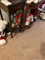 Side view of dark wood side table with drawer and shelf, showing wear and holiday decorations (contents not included).