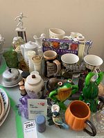 Overview of assorted items including mugs, decorative frogs, salt and pepper sets, glass and ceramic pieces